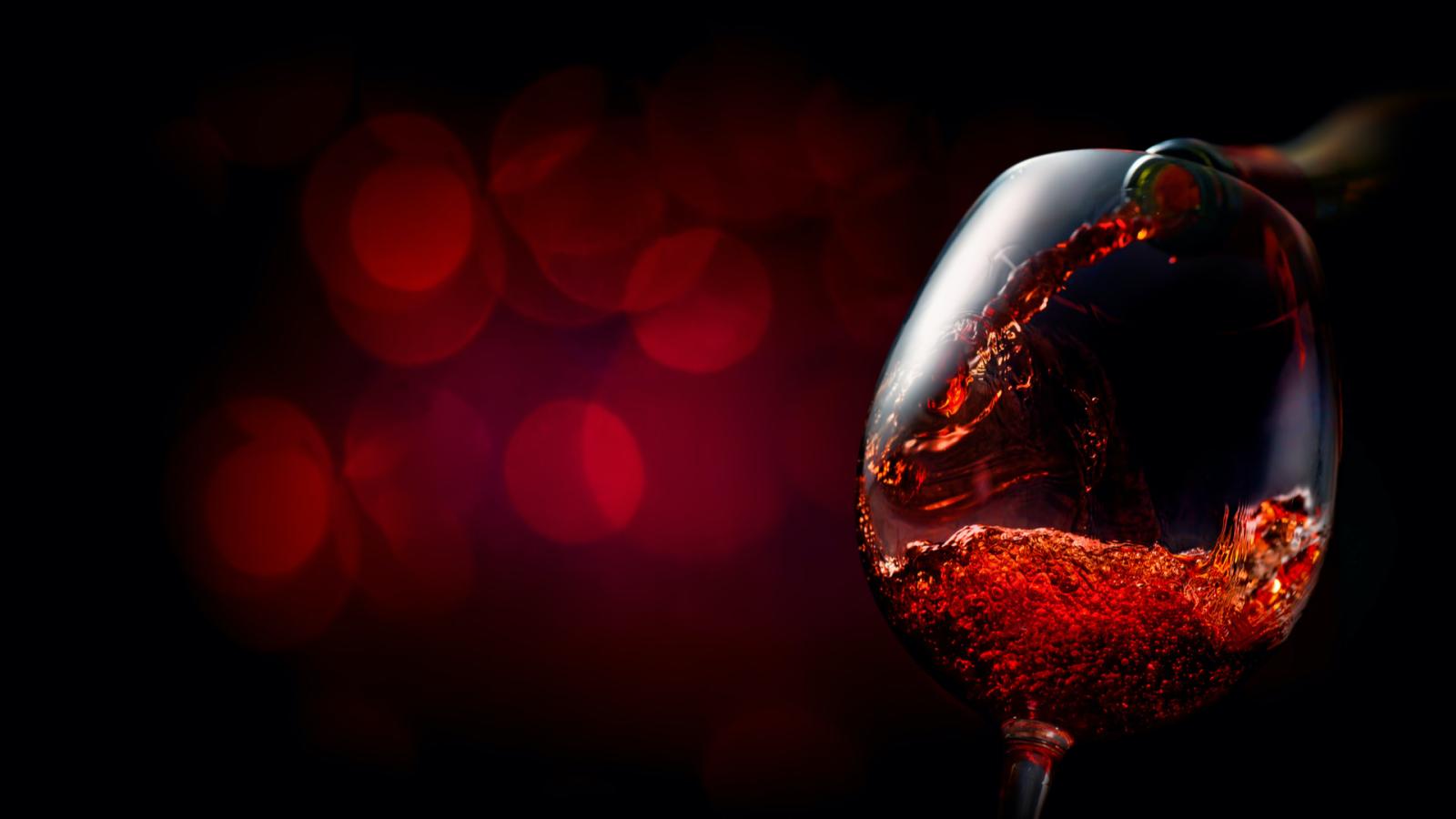 A glass of red wine being poured.